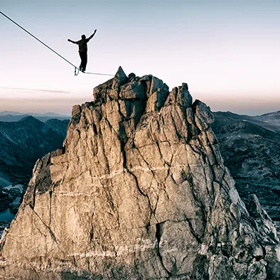 A person tightroping towards a mountain